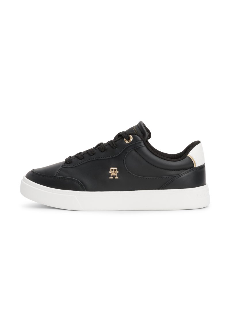 Sneaker in pelle nera con suola in gomma bianca, dotati di lacci neri, un emblema dorato e un accentuazione bianca a contrasto sul tallone.