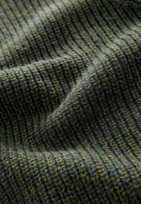 Tissu vert texturé avec un motif en nervures, comportant des fils verts foncés et clairs tissés ensemble, créant une apparence douce et superposée.