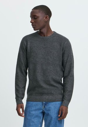 Dark gray knit sweater with a crew neckline, ribbed cuffs, and hem. Paired with light blue denim jeans, showcasing a relaxed fit.