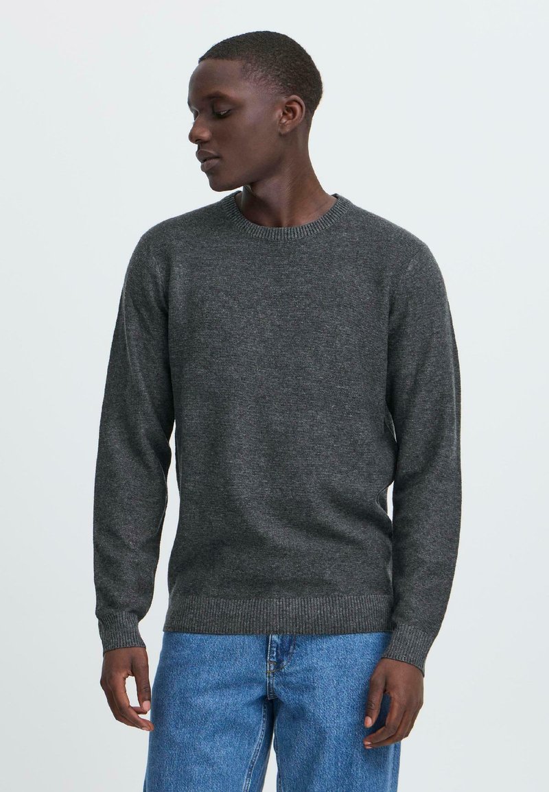 Mørkegrå strikket genser med rund halslinning, ribbede mansjetter og nedkant. Kombinert med lyseblå denimjeans som har en avslappet passform.