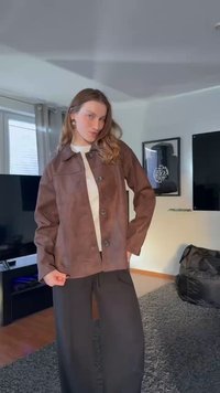 Brown suede jacket with a pointed collar, front buttons, and long sleeves, paired with black wide-legged pants. Simple design, no patterns.