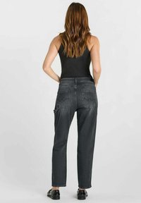 Jeans en denim noir avec une coupe décontractée, des jambes droites et des poches arrière distinctives avec des détails de surpiqûres courbes.
