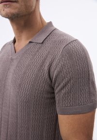 Gebreid polo shirt in gedempt taupe, met een textuurpatroon, V-hals, korte mouwen en ribgebreide manchetten.