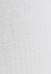 Tejido blanco con canalé y rayas texturizadas verticales, que muestran un fino detalle de punto y sutiles líneas horizontales.