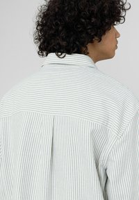 Chemise à rayures avec un tissu léger présentant des lignes verticales bleues et blanches, un col à pointes écartées et un empiècement dos. Texture avec une coupe décontractée.