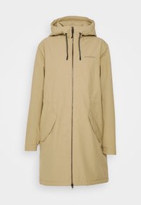 Manteau beige à capuche longueur genoux avec fermeture éclair à l'avant, deux poches à rabat, poignets élastiques et cordons noirs sur la capuche.