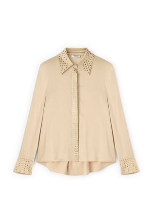 Beige langærmet skjorte med nitter på kraven og manchetterne. Glat stof, afslappet pasform, kobberfarvede nitter langs sømmene, og afrundet kant.