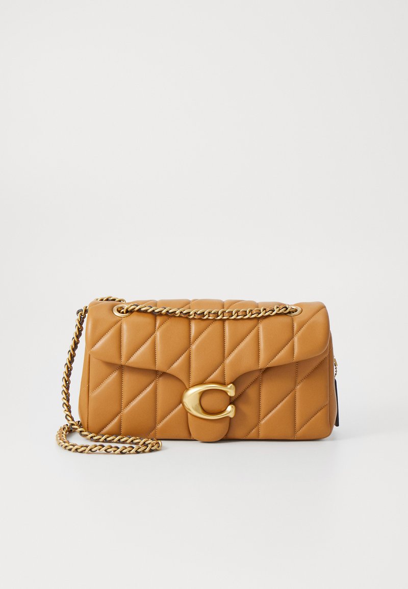 Borsa a tracolla trapuntata color beige con catena dorata, dotata di una grande chiusura circolare dorata sulla parte anteriore e di una morbida texture in pelle.