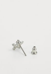 Boucles d'oreilles en argent en forme d'étoiles, avec un tige fine et un fermoir rond. Présentent une finition métallique polie et des détails de design complexes.