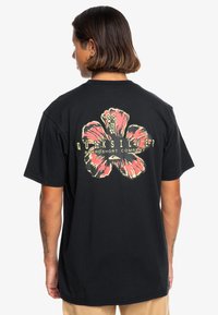 Mustapaita lyhyillä hihoilla, jossa on suuri vaaleanpunainen hibiskuskuvio selässä ja keltainen teksti 'Quiksilver Boardshort Company'.