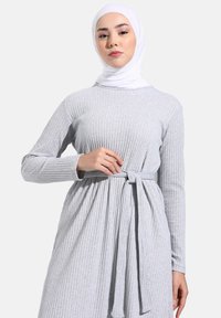 Harmaa ribbattu pitkähihaisuus mekko, jossa on solmittu vyö vyötäröllä. Pehmeä kangas, jossa on struktuuripinta, ja siinä on pyöreä pääntie sekä täyspitkät hihat.