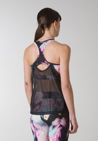 Racerback fitness tanktop i sort mesh med blomstermønster. Nøgnehulsdetalje på ryggen. Letvægts, åndbart stof.