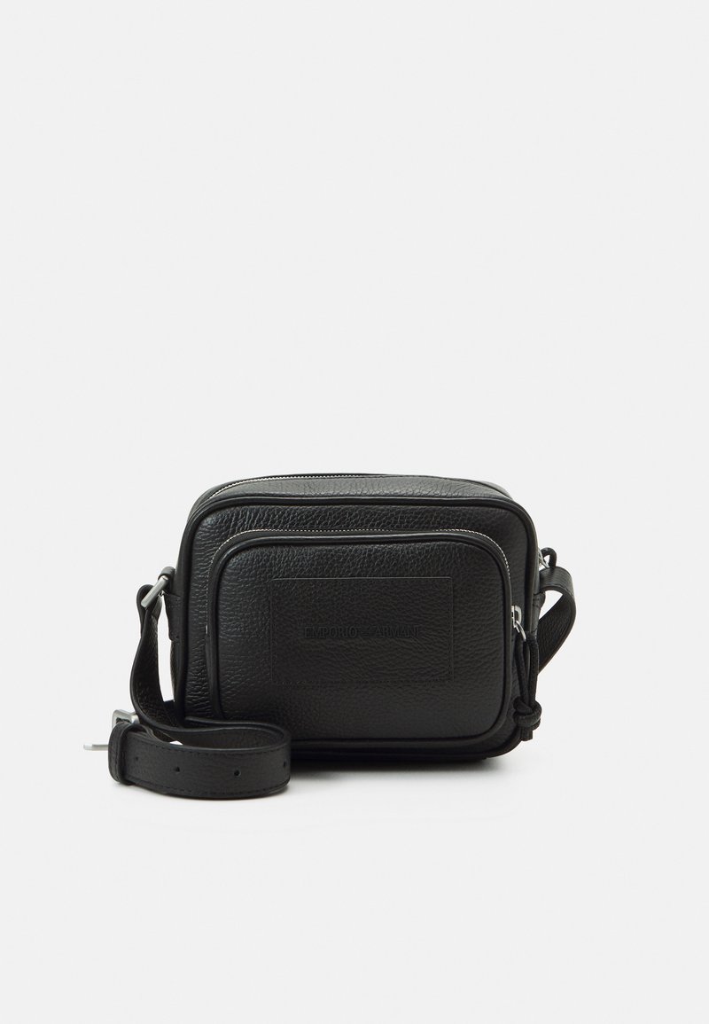 Μαύρη δερμάτινη τσάντα ώμου με δομημένο ορθογώνιο σχήμα, υφή στην επιφάνεια, μπροστινή τσέπη με φερμουάρ και ρυθμιζόμενο λουρί. Εγκεφαλική στάμπα του λογότυπου.