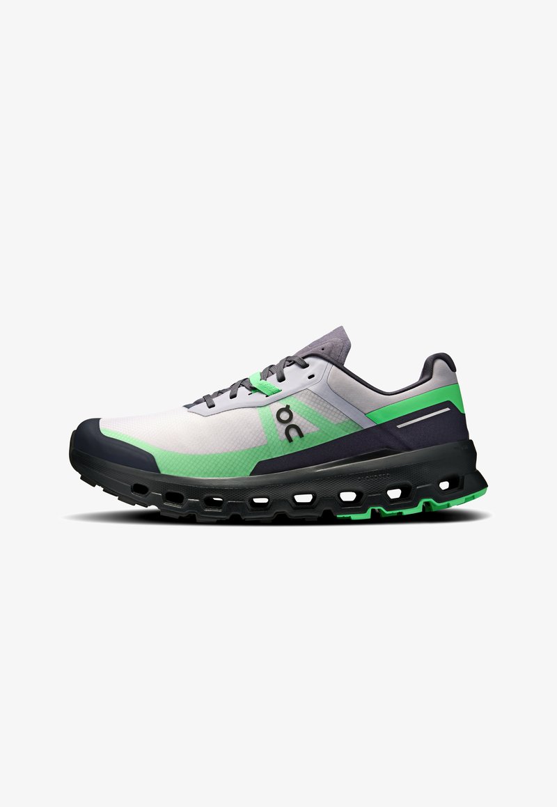 Les chaussures de course présentent un dessus gris et blanc avec des accents verts, un design en mesh texturé et une semelle noire épaisse avec des découpes.
