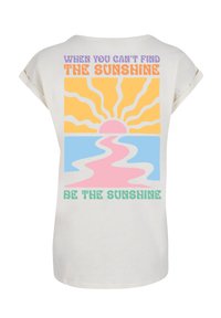Cremfarbendes T-Shirt in lockerer Passform mit einem bunten grafischen Design, das Sonne, Wasser und den Text "Wenn du die Sonne nicht finden kannst, sei die Sonne" zeigt.