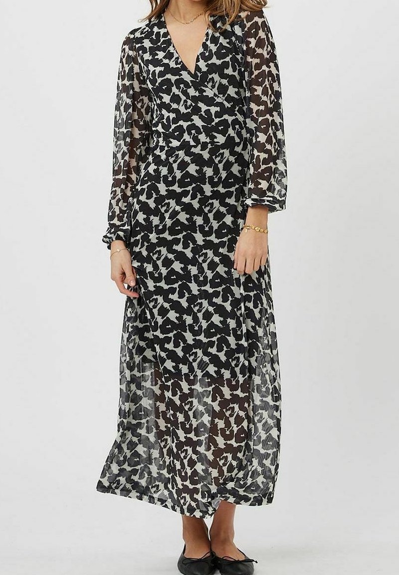 Robe longue à manches longues en noir et blanc avec un voile transparent et un motif abstrait. Elle présente un décolleté en V et une silhouette fluide.
