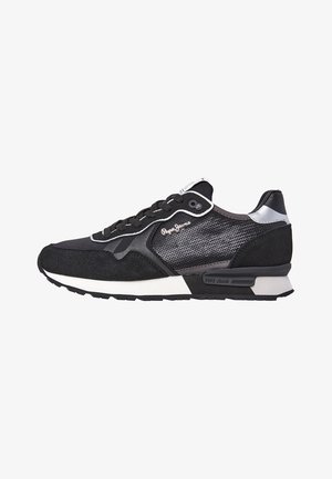 Black sneaker with mesh and suede upper, white outsole, silver accents, and black laces. Features logo on the side and a cushioned sole.