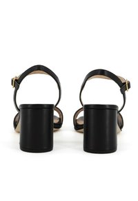 Sandali neri con tacco a blocco spesso, cinturino alla caviglia regolabile e materiale in pelle liscia con soletta beige.