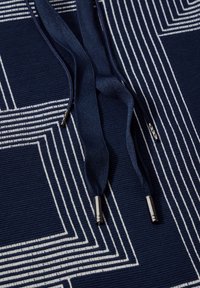 Marineblauer Stoff mit weißen Linienmustern, ausgestattet mit dunkelblauen Kordeln mit metallischen Enden. Strukturiertes Oberfläche.