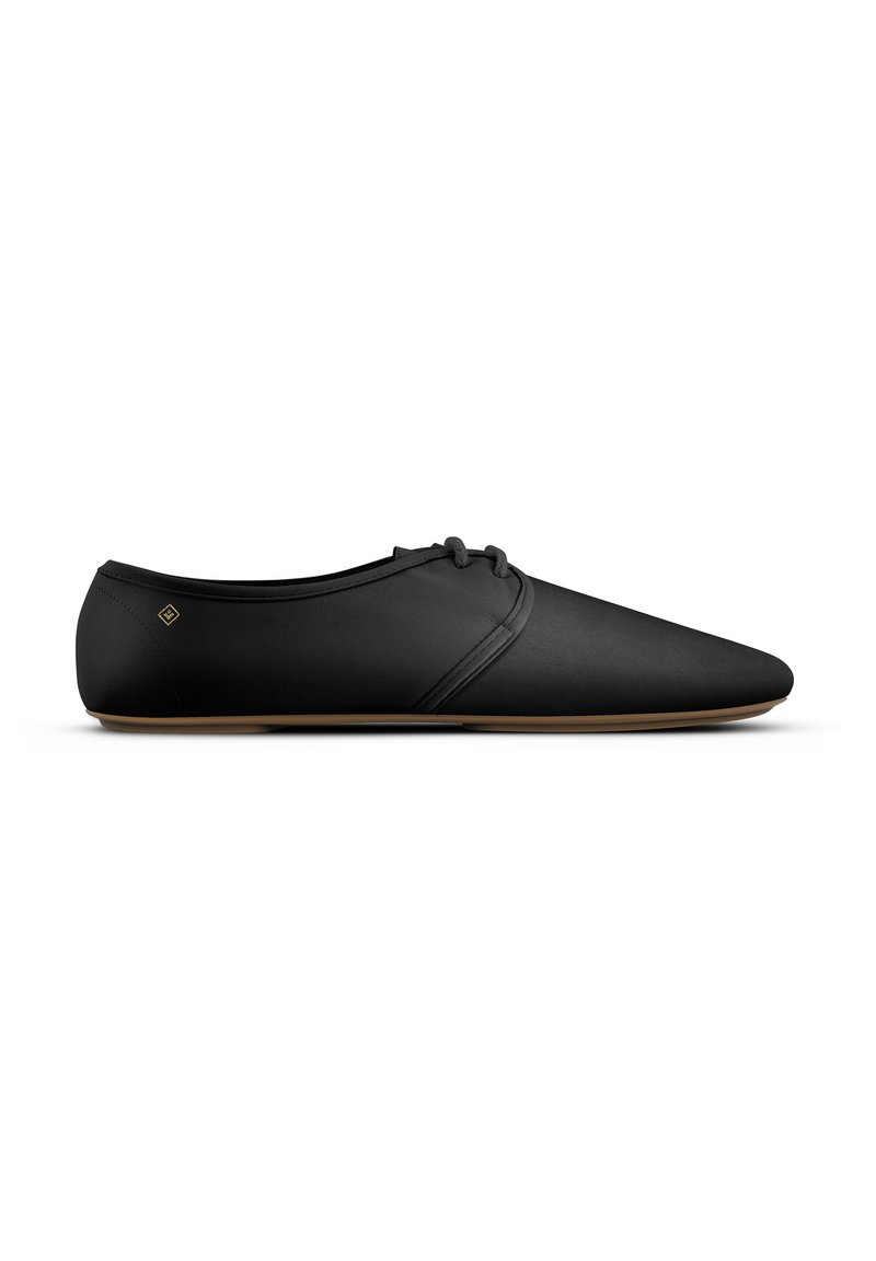 Zwarte minimalistische leren veterschoen met smalle, puntige neus en lichtbruine zool, weergegeven in zijprofiel op een witte achtergrond.
