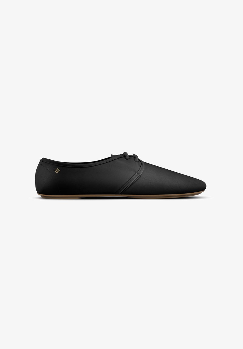 Zwarte minimalistische leren veterschoen met smalle, puntige neus en lichtbruine zool, weergegeven in zijprofiel op een witte achtergrond.
