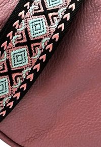 Roze leer met een gestructureerde afwerking, voorzien van een geweven band die geometrische patronen in zwart, muntgroen en koraalkleur weergeeft.