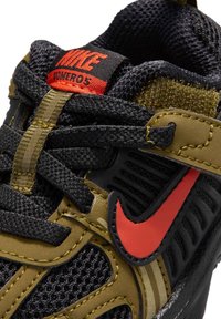 Buty do biegania Nike z czarną cholewką z siateczki, oliwkowymi nakładkami, czerwonymi akcentami i grubymi sznurowadłami. Na bokach widoczne teksturowane wzory.