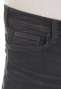 Jeans de mezclilla negra con un corte ajustado, cintura de altura media, y un bolsillo frontal con costuras visibles y detalles de hardware metálico.