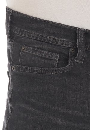 Schwarze Denim-Jeans mit schlankem Schnitt, mittelhoher Taille und einer Vordertasche mit sichtbaren Nähten und metallischen Akzenten.