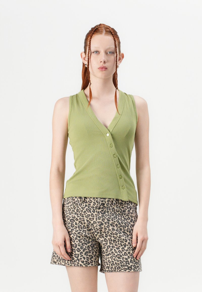 Top de tirantes verde acanalado con escote en V y botones en la parte frontal, combinado con pantalones cortos de estampado de leopardo con un corte holgado y cintura elástica.