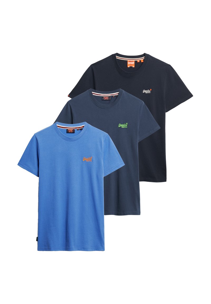 Drie katoenen T-shirts gestapeld: één lichtblauw, één marineblauw en één donker marineblauw. Elk heeft een klein geborduurd logo op de borst.