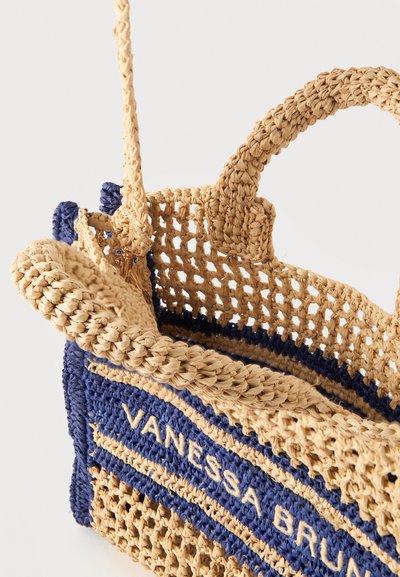 Sac à main en paille tressée avec des rayures bleues, avec le texte "Vanessa Bruno" et deux poignées sur fond blanc.