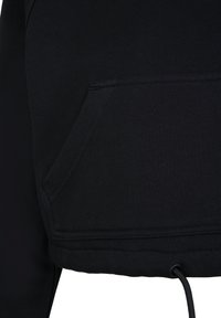 Gros plan d'une poche en tissu noir avec des coutures visibles et une boucle de cordon au bas d'un vêtement.