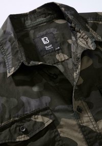 Bavlnená maskáčová košeľa v zelených a čiernych odtieňoch, s límcom na špic, zapínaním na gombíky a značkovou etiketu vo vnútri krku.