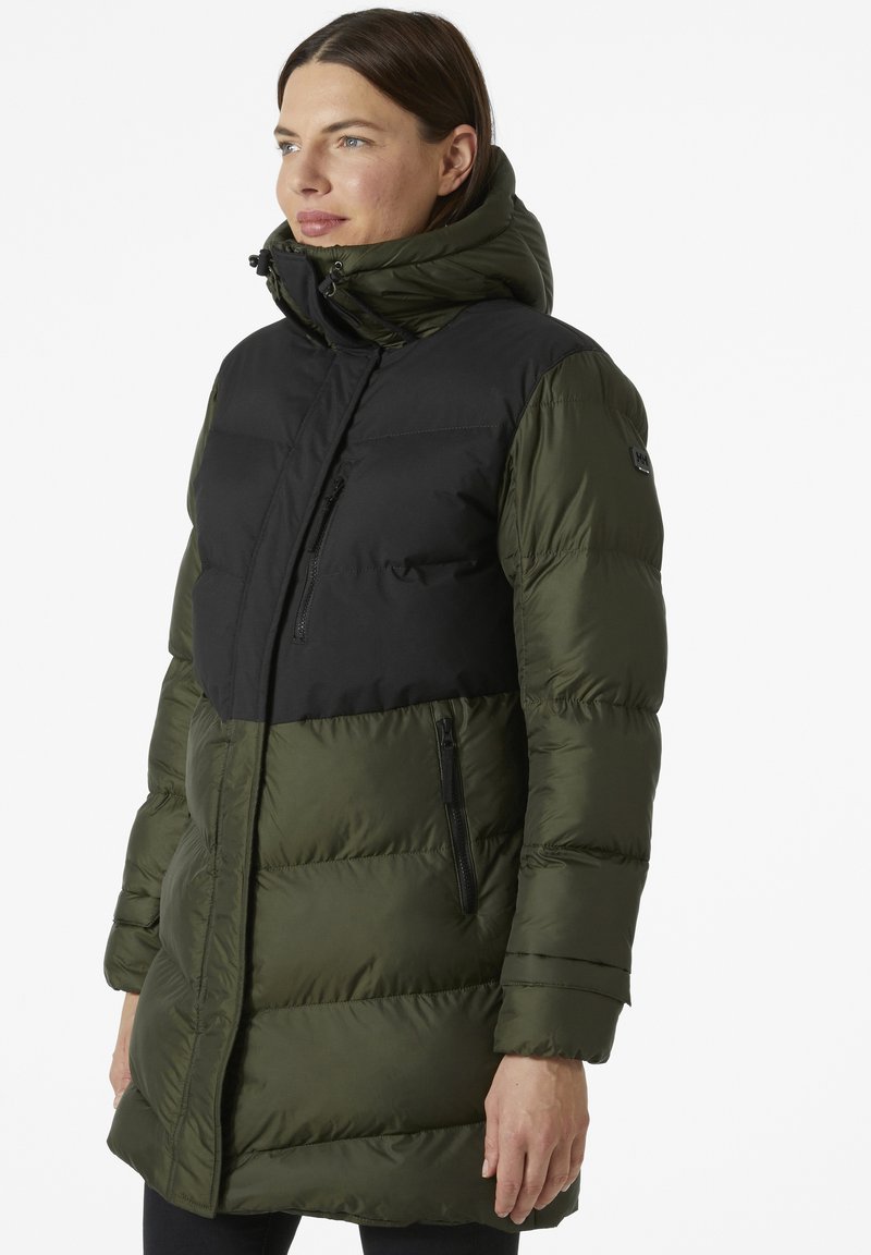 Abrigo acolchado con una sección superior negra y una sección inferior verde, con un cuello alto, bolsillos con cremallera y un acabado texturizado.