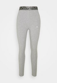 Grå bomuldsleggings med en sort talje med "CALVIN KLEIN" tekst og et lille hvidt logo på den nederste del af benet. Glat tekstur.
