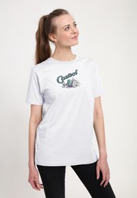 Bílý bavlněný tričko s grafickým potiskem se slovem "Castrol" a designem historického závodního auta v zelené a šedé barvě. Krátké rukávy.