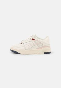 Baskets beige clair en cuir avec des accents roses et rouges, dotées d'un talon texturé, de lacets et d'une semelle en caoutchouc.