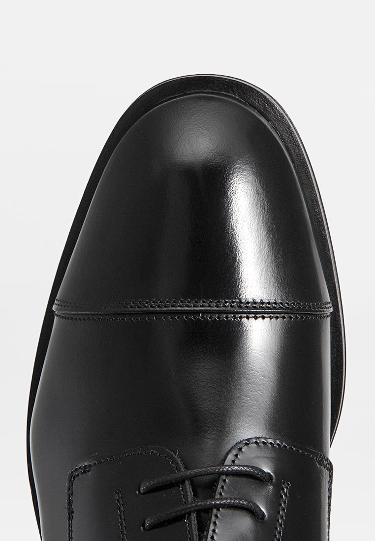 Schwarzer Lederschuh mit runder Spitze, polierter Oberfläche, Schnürdesign und einem subtilen Stichdetail entlang des Obermaterials.