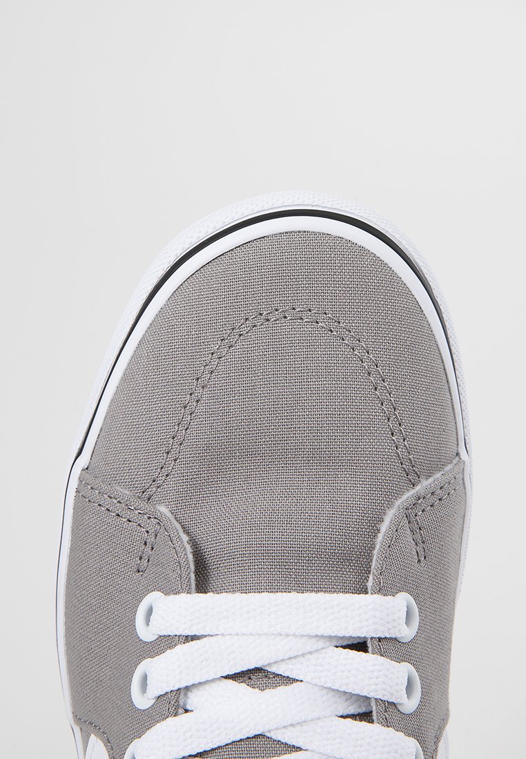 Zapatilla de lona gris con cordones blancos, con puntera redonda, suela de goma negra y detalles de costura. Diseño minimalista, sin logotipos visibles.