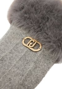 Accesorio gris de felpa con un suave puño de piel gris. Cuenta con un cierre de metal en tono dorado con un diseño circular y detalle de logo.