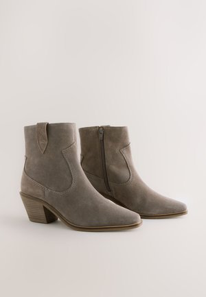 Suède enkellaarsjes in lichtgrijs met een spits toelopende neus, ritssluiting aan de zijkant en een gestapelde hak met horizontale groeven.