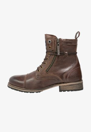 Bota corta de cuero marrón con cordones, cremallera lateral, costuras decorativas, tira para tirar en el talón y tacón bajo apilado de madera.