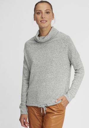 Sivi pullover s kapuljačom izrađen od mekog materijala, s dugim rukavima i detaljem sa vezicom na rubu, u kombinaciji s smešnim kožnim hlačama.