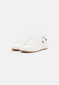 Hvite lær sneakers med en strukturert overflate, med en rød logo akcent, flate snørebånd og en såle av gummigummi. Minimalistisk design.