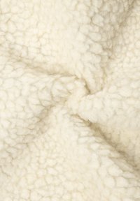 Tessuto sherpa di colore crema, morbido, con una superficie morbida e testurizzata e piccoli motivi in pile arrotondati.