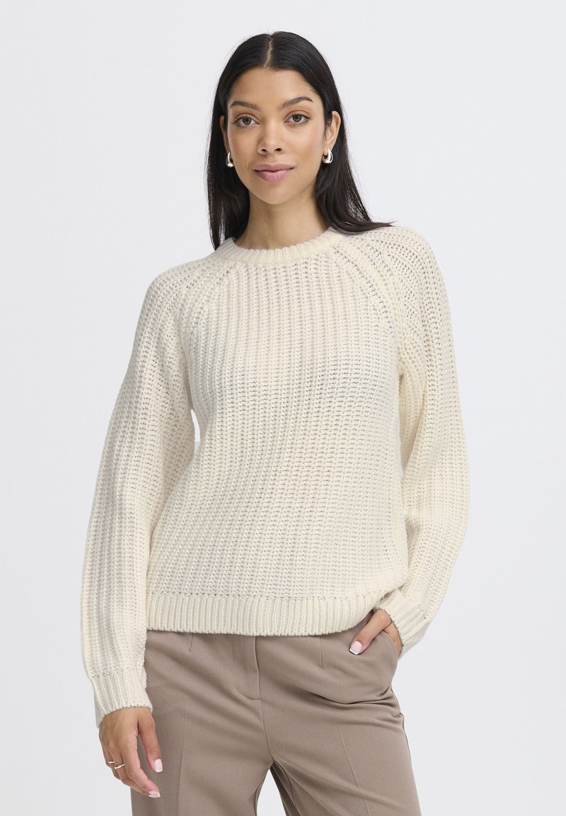 Pull en tricot couleur crème avec un motif texturé, des poignets et un ourlet côtelés. Doté d'un col rond et d'une coupe légèrement ample.