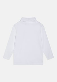 Polo shirt à manches longues, blanc, avec un col roulé, fabriqué en coton doux, présentant un design sobre et des poignets cousus.