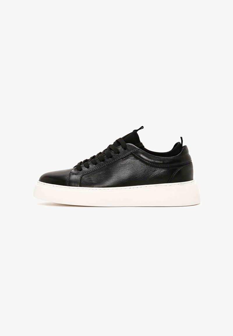 Czarne skórzane sneakersy z zaokrąglonym noskiem, sznurowanym zapięciem i białą gumową podeszwą. Gładka faktura zminimalizowana detali oraz pętla przy pięcie.