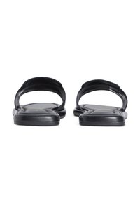 Μαύρα σανδάλια με δύο καμπύλες λουράκια και επίπεδη σόλα. Ομαλή υφή με ελάχιστο σχεδιασμό. Η σόλα διαθέτει ελαφριά καμπύλωση για άνεση.